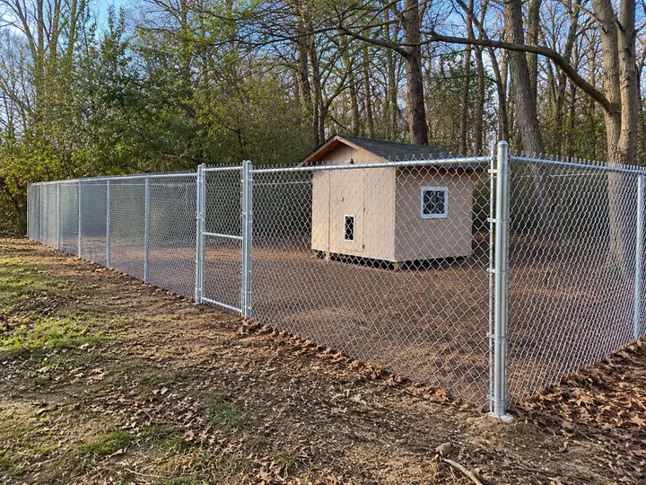 Galvanized chain link fence enclosing a yard with a storage shed