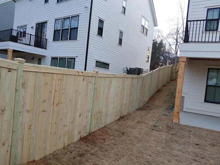 Wood privacy fence with solid vertical boards along a townhome side yard
